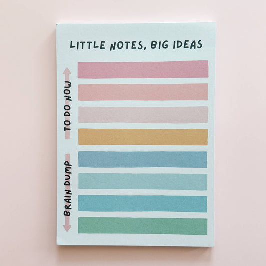 Notebook with colorful striped pages and text on a light pink background
