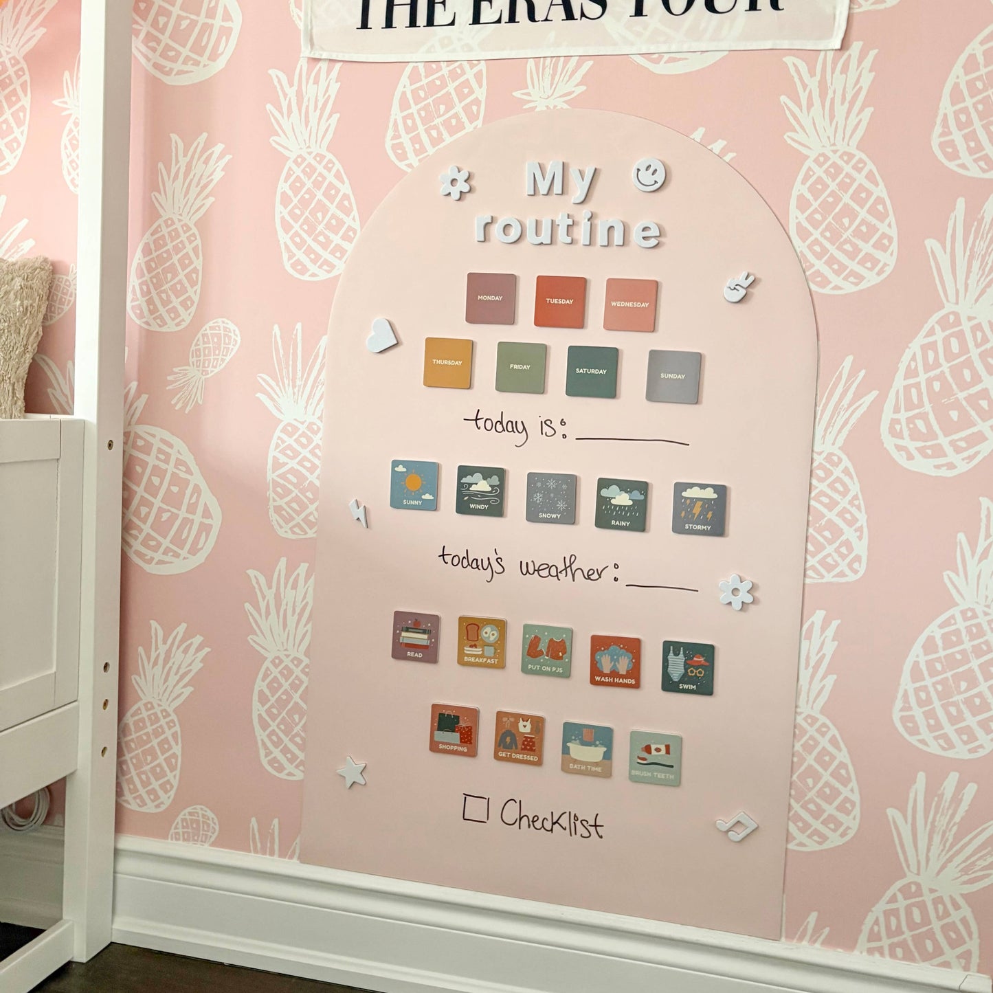 Mila May themed wall with decorative elements and a poster on a pink pineapple-patterned wall.