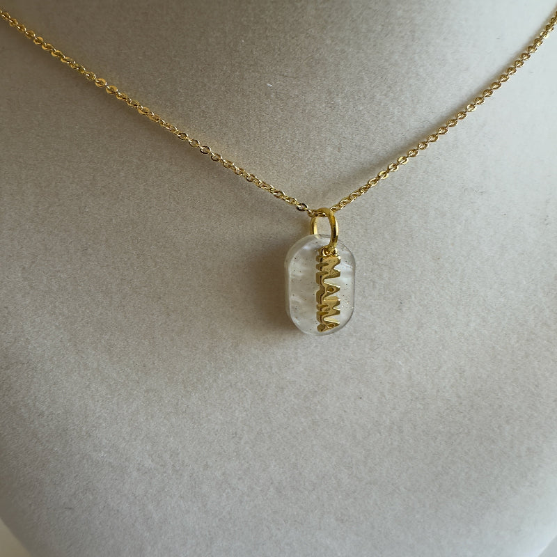 Gold necklace with a pendant on a light gray background