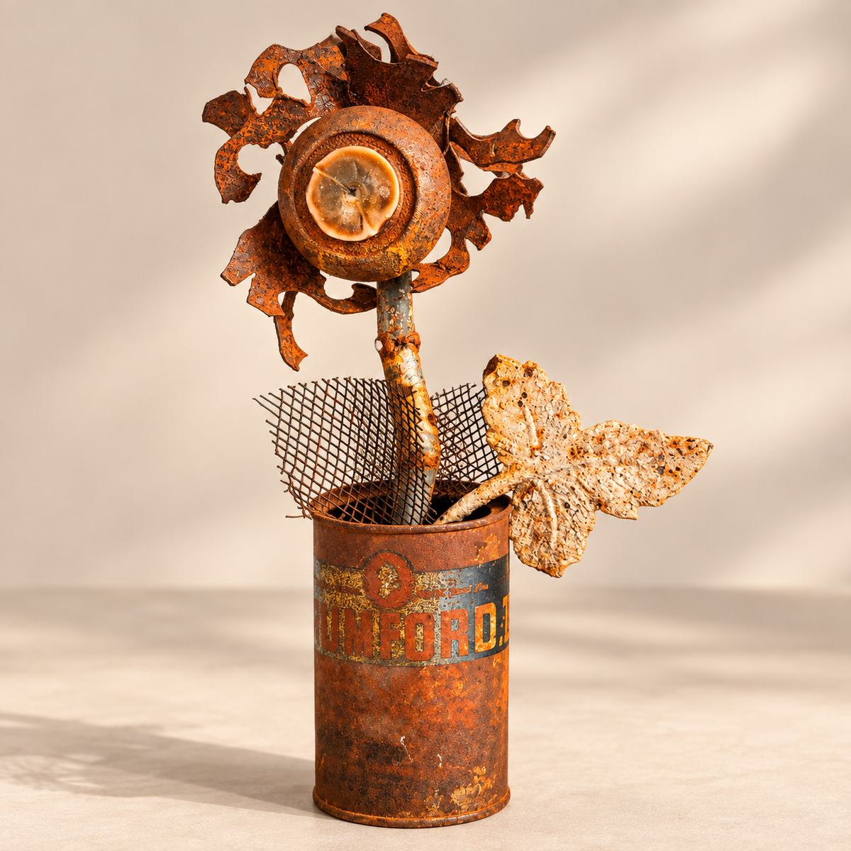 One-of-a-kind reclaimed metal flower sculpture featuring a vintage Rumford tin can, rusted steel petals, wire mesh and cast metal leaf.