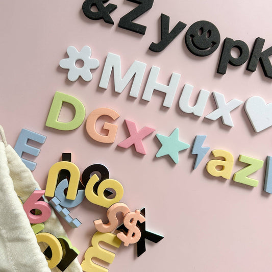 Colorful plastic letters and symbols on a pink background