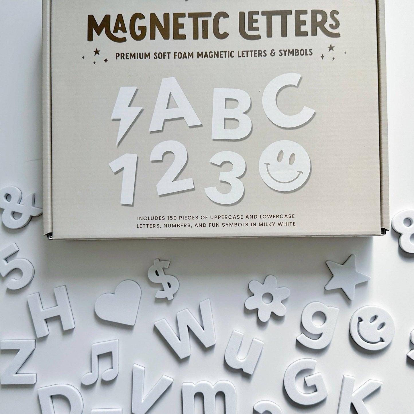 Box of magnetic letters and symbols with scattered letters on a light background