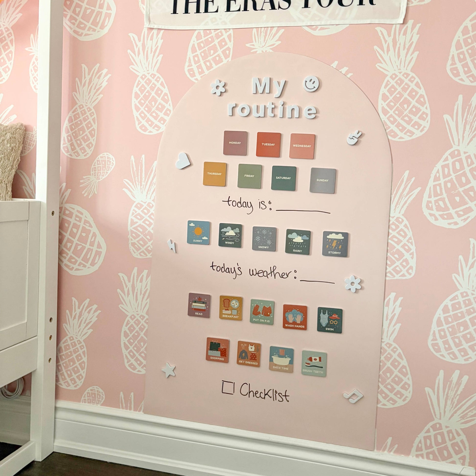 Mila May themed wall with decorative elements and a poster on a pink pineapple-patterned wall.