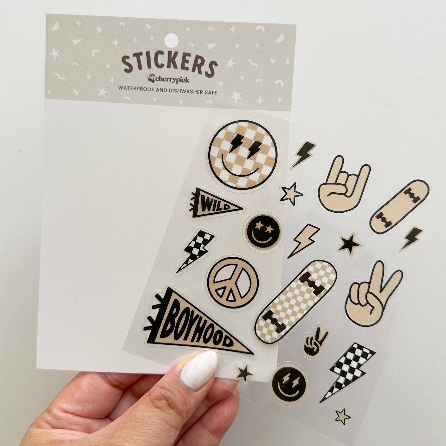 Sheet of stickers with various designs held by a hand against a light gray background